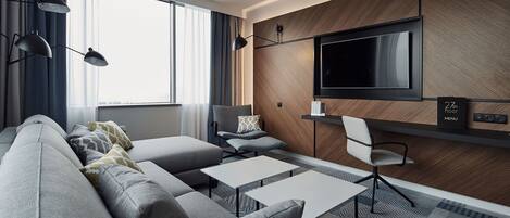 A modern living room with a sofa, two tables, a TV, and a chair.
