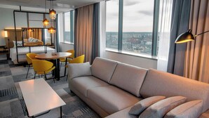 Une chambre d’hôtel moderne équipée d’un canapé, d’une table à manger, de chaises et offrant une vue sur la ville.