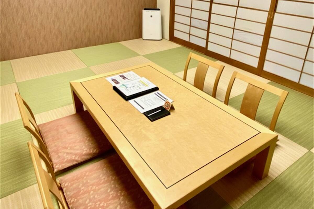 A traditional Japanese tatami mat room with a wooden table and chairs.