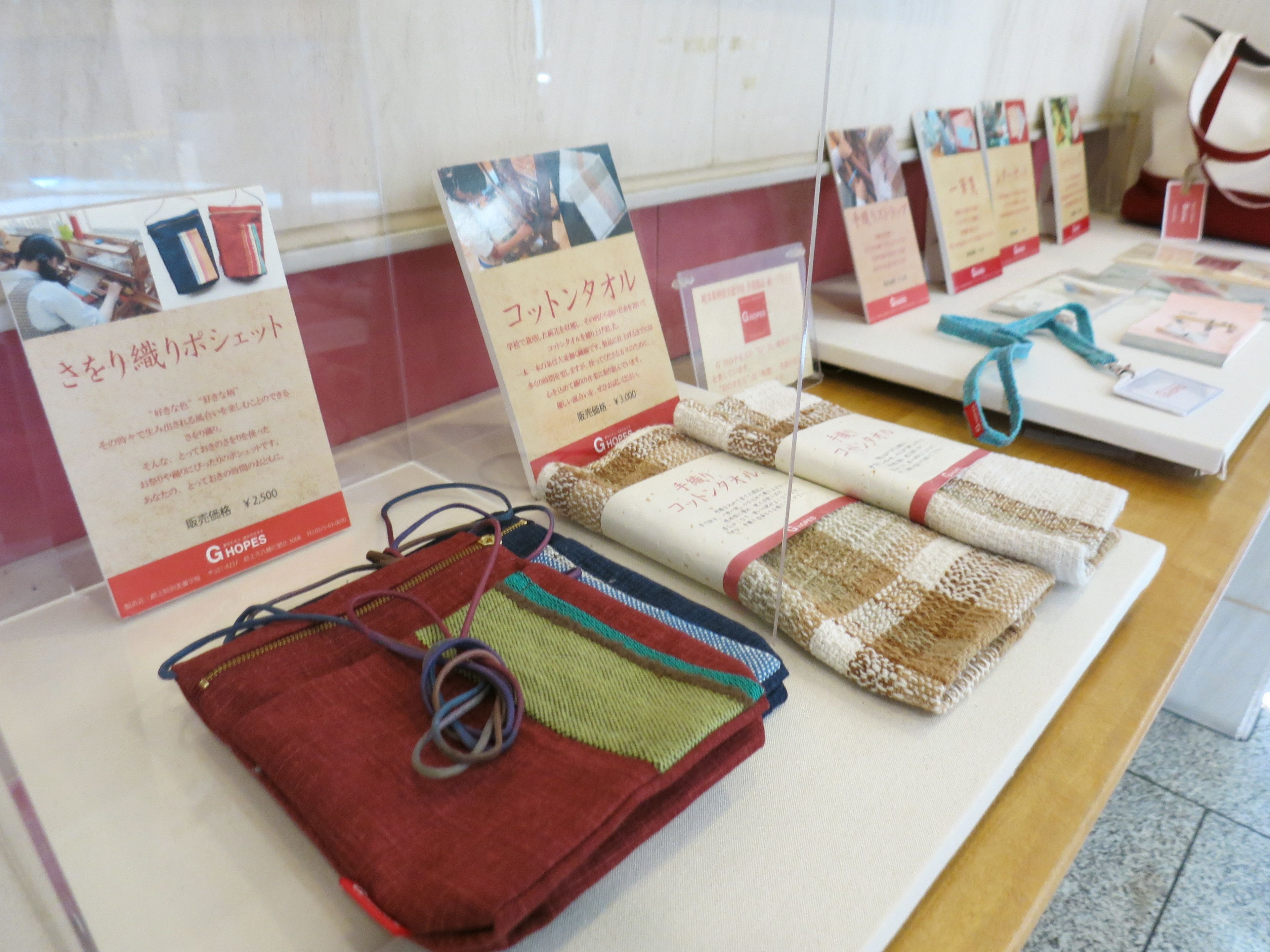 A display of woven bags with price tags and informational signs.