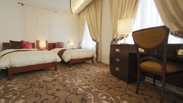 A hotel room with two beds, a desk, and a chair.