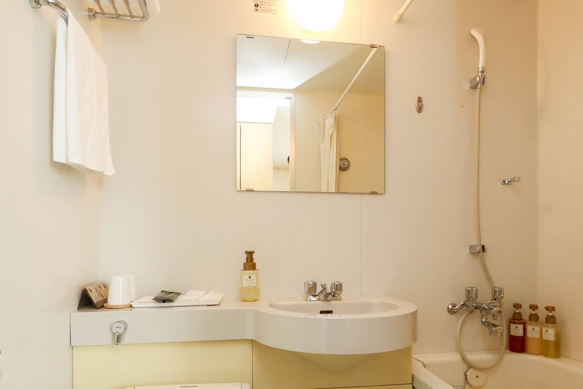 A bathroom with a toilet, sink, mirror, and shower.
