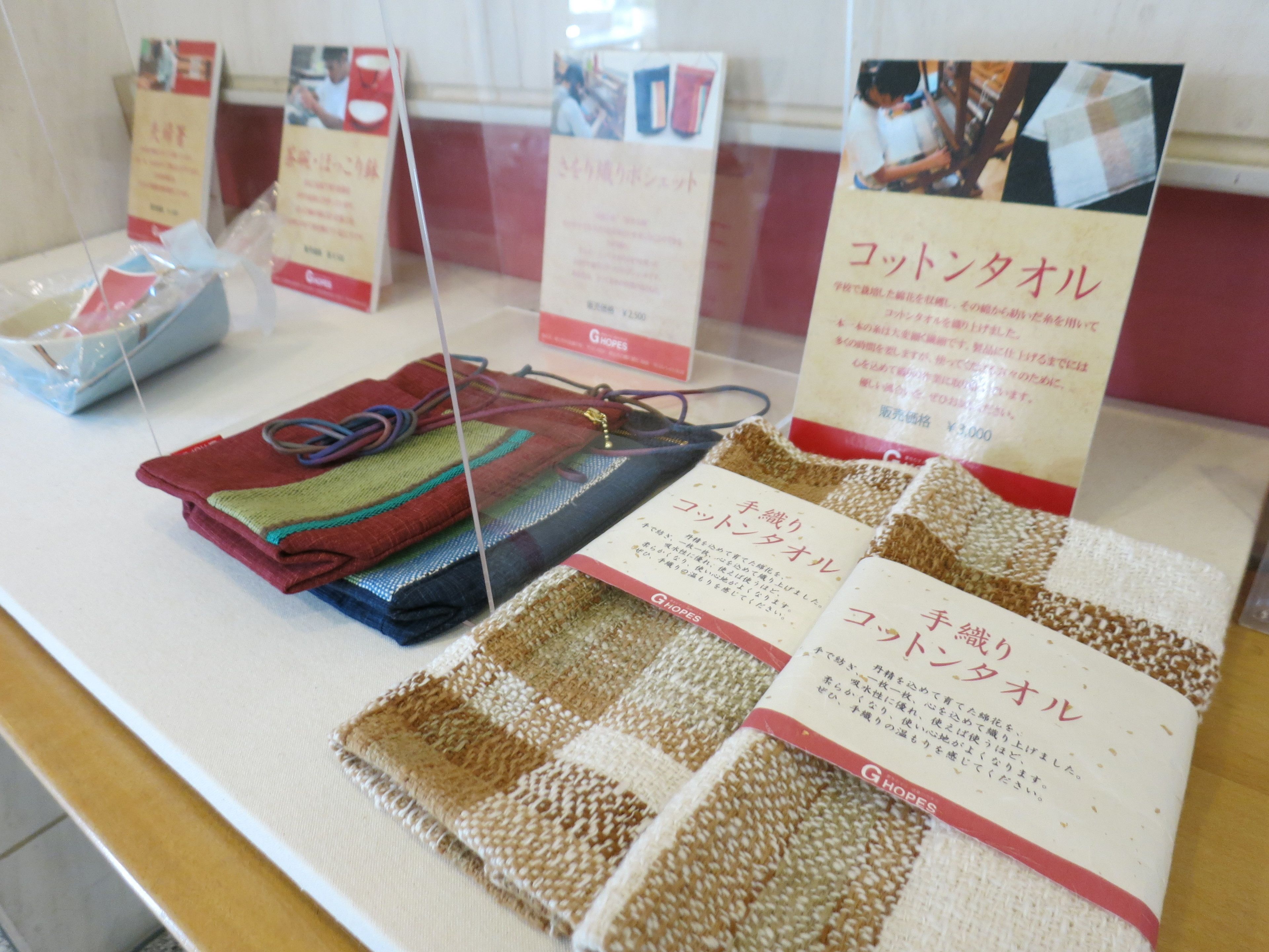 A display of woven textiles and a handbag with a price tag.