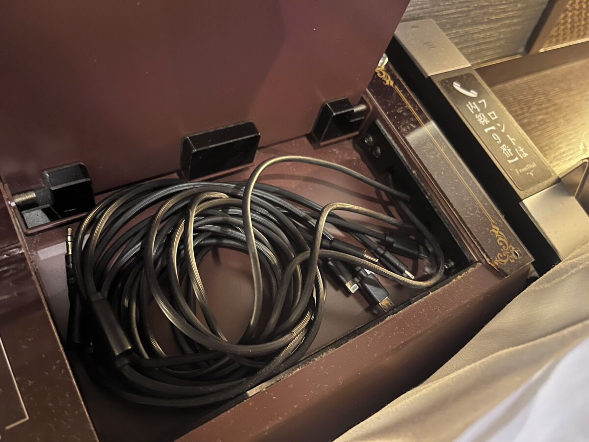 Un cajón con un cable enrollado y un dispositivo electrónico negro.