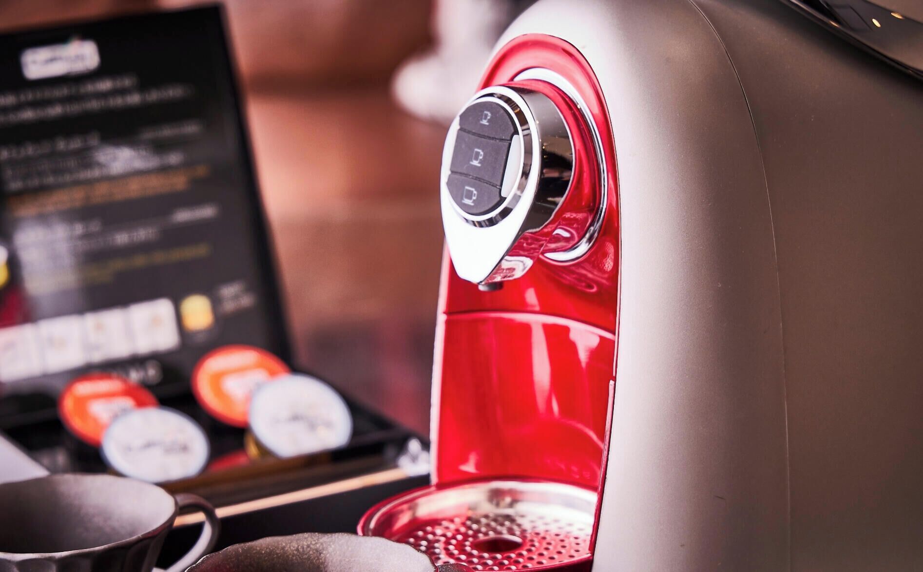 En kaffemaskine med kontrolpanel og en menu i baggrunden.