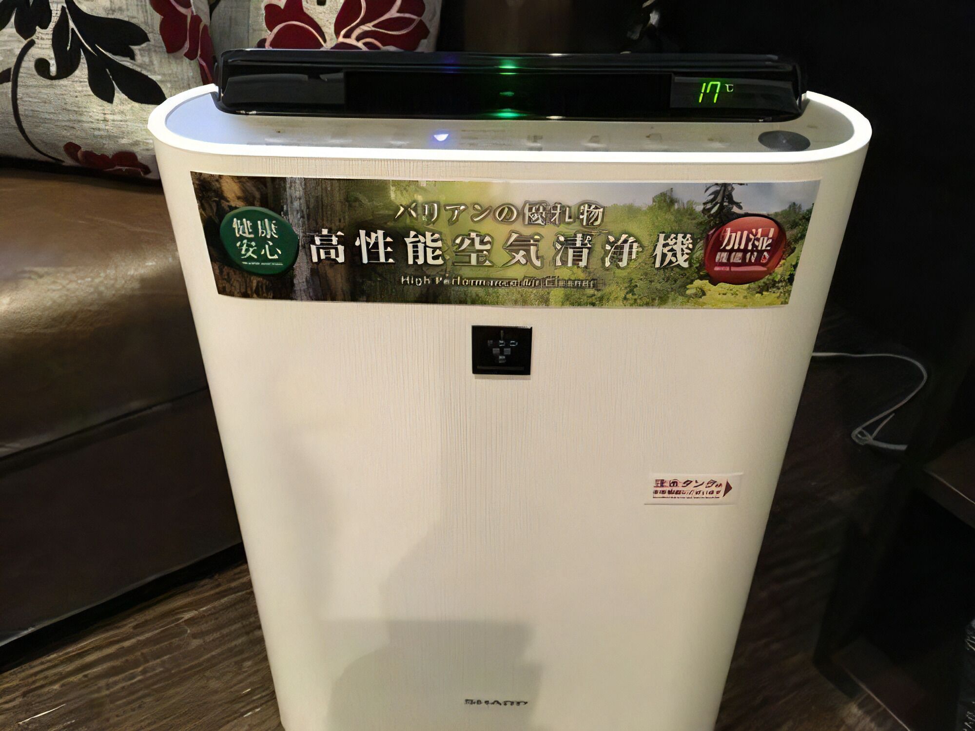 A white appliance with a digital display and stickers indicating it is a high-performance air purifier.