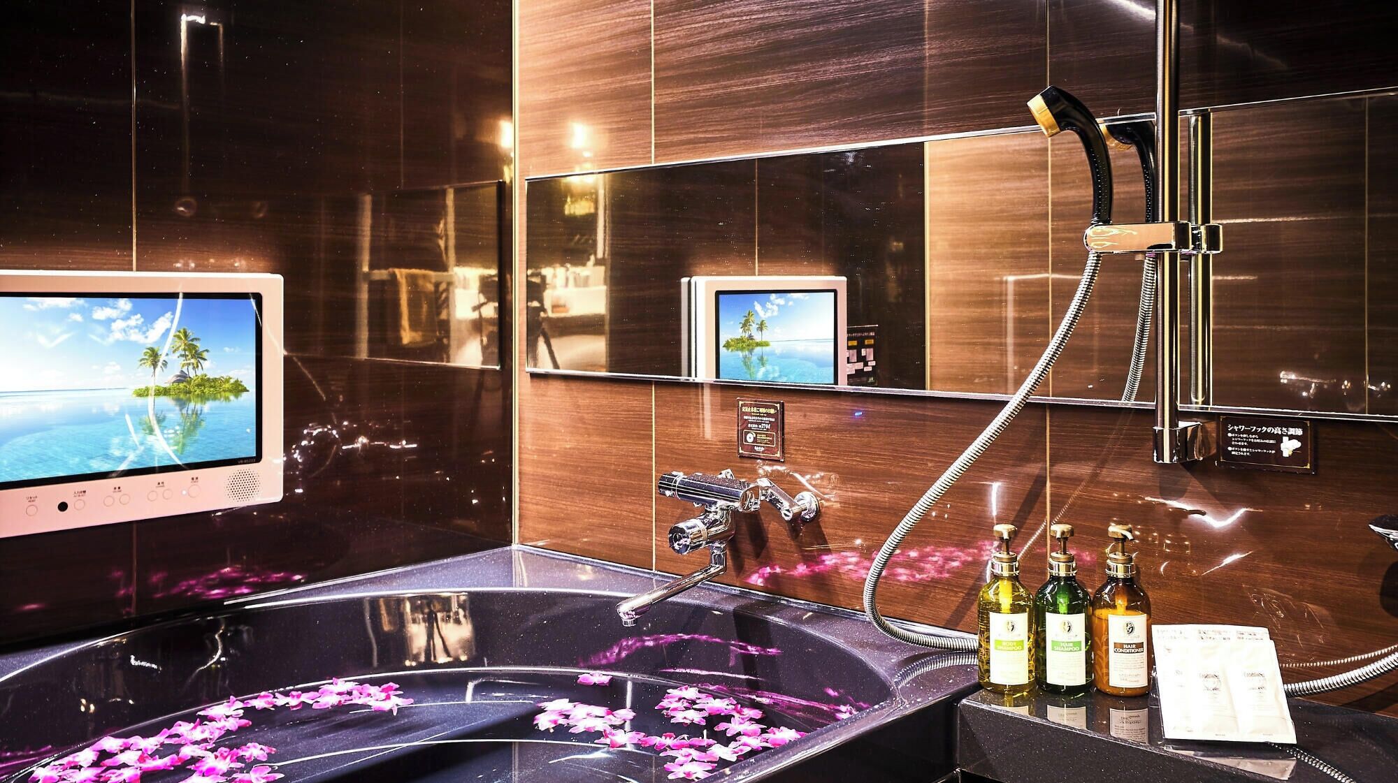 A bathroom with a large bathtub, a handheld showerhead, and a vanity with a mirror.