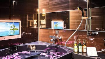 A bathroom with a large bathtub, a handheld showerhead, and a vanity with a mirror.