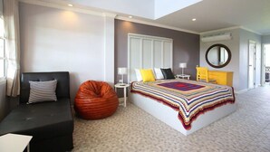 Un dormitorio moderno con una cama grande, un sofá, un sillón de peluche y una mesita.