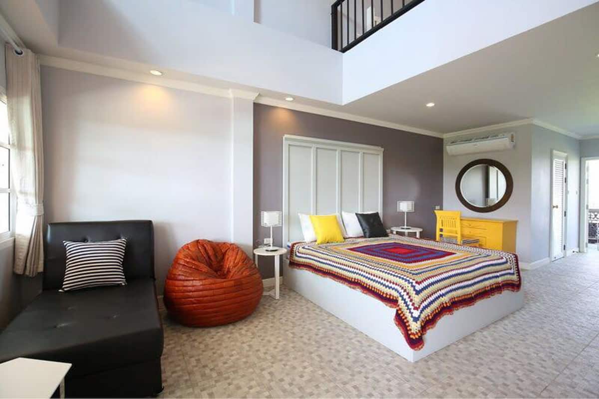 Een moderne slaapkamer met een groot bed, een bank, een relaxfauteuil en een klein tafeltje.