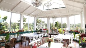 Un invernadero espacioso con techos altos, ventanas amplias y elegantes candelabros.