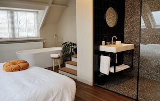 A modern bathroom with a freestanding bathtub, a vanity with a sink, and a large mirror.
