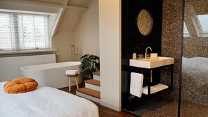 A modern bedroom with a large bed, a window with blinds, a wooden stool, and a plant. - Moeke Mooren (Appeltern)