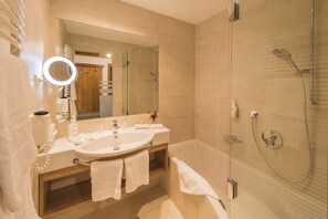 A modern bathroom with a large sink, mirror, and glass-enclosed shower. -  Hotel Spielmann (Ehrwald)
