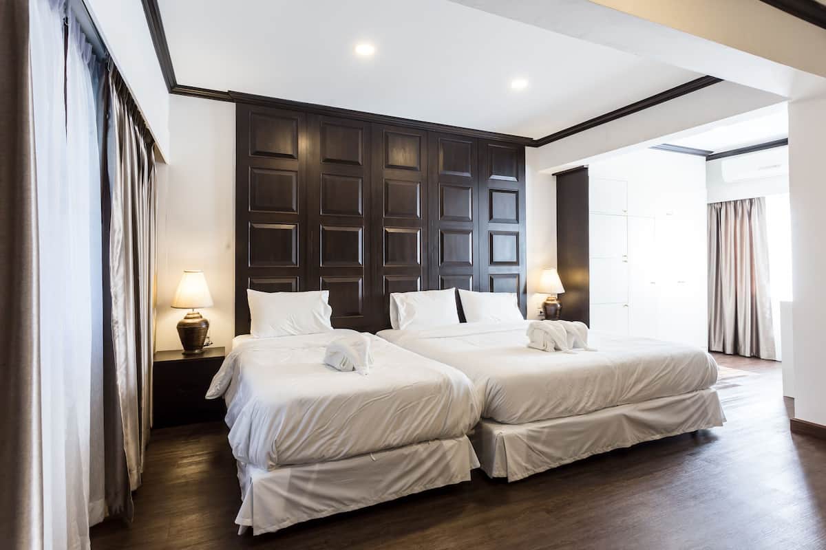 Habitación de hotel con dos camas, paneles de madera oscura en la pared y un ventanal grande.