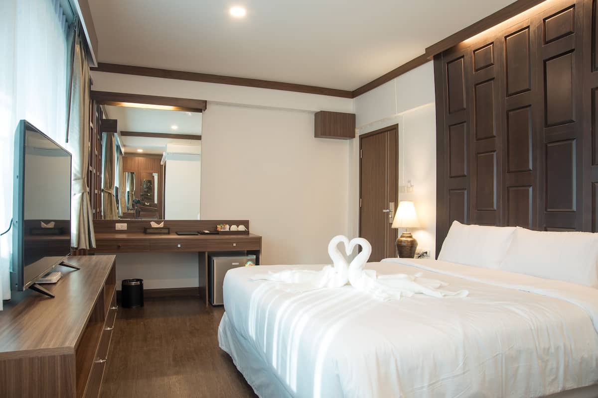 Una habitación de hotel con una cama grande, un escritorio, un espejo y un armario.