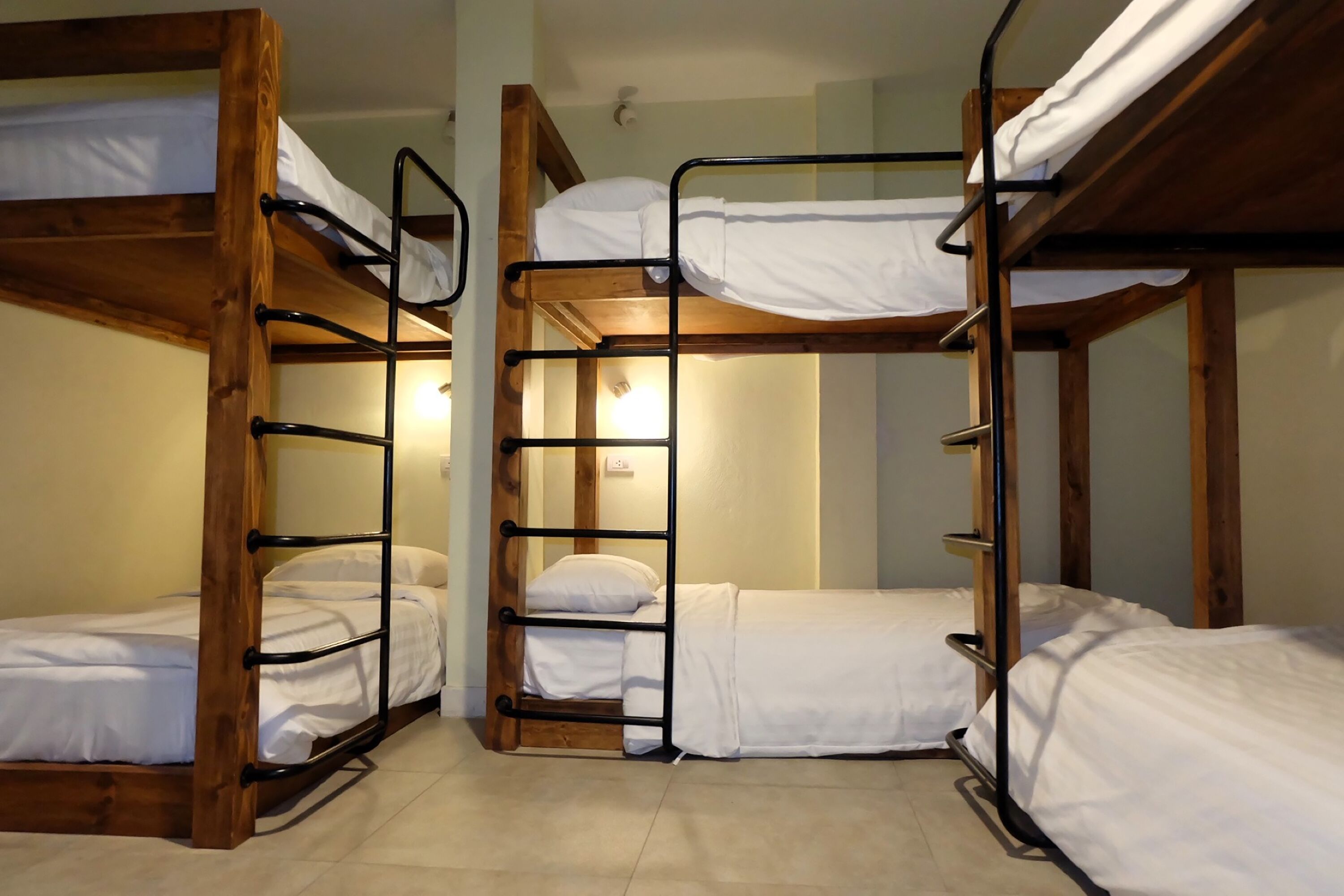 A bunk bed room with wooden frames and white bedding.