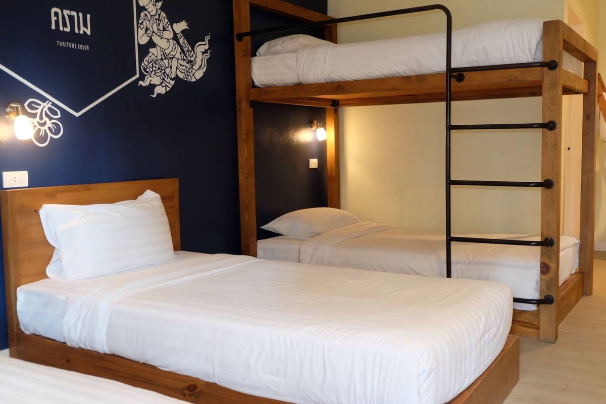 Quarto com beliche, cabeceira de madeira, roupa de cama branca e um enfeite na parede.