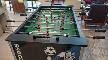 A foosball table with a soccer theme, located in a room with a sofa and a coffee table.