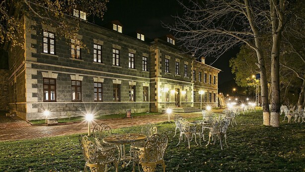 Un edificio histórico de piedra con múltiples ventanas y una entrada bien iluminada.