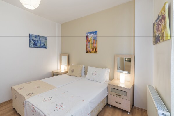 A bedroom with a bed, bedside tables, a mirror, and artwork on the walls.