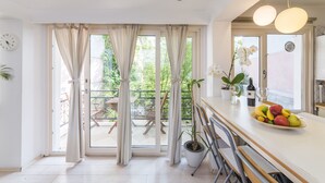 Une cuisine moderne dotée d’une grande fenêtre, d’un coin repas et d’un balcon aménagé avec du mobilier d’extérieur.