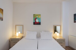 Un dormitorio con una cama grande, dos mesitas de noche con lámparas, un cuadro en la pared y una ventana.