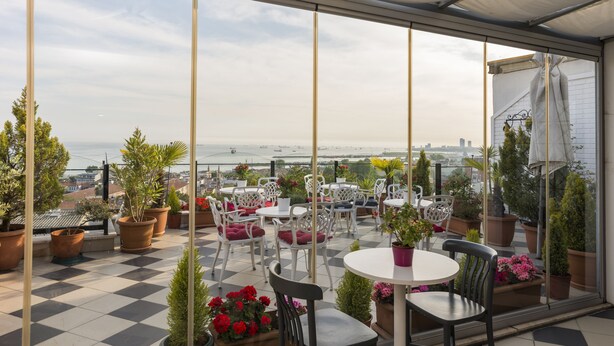 Une terrasse dotée d’un sol à carreaux, de plantes en pot et de mobilier d’extérieur.