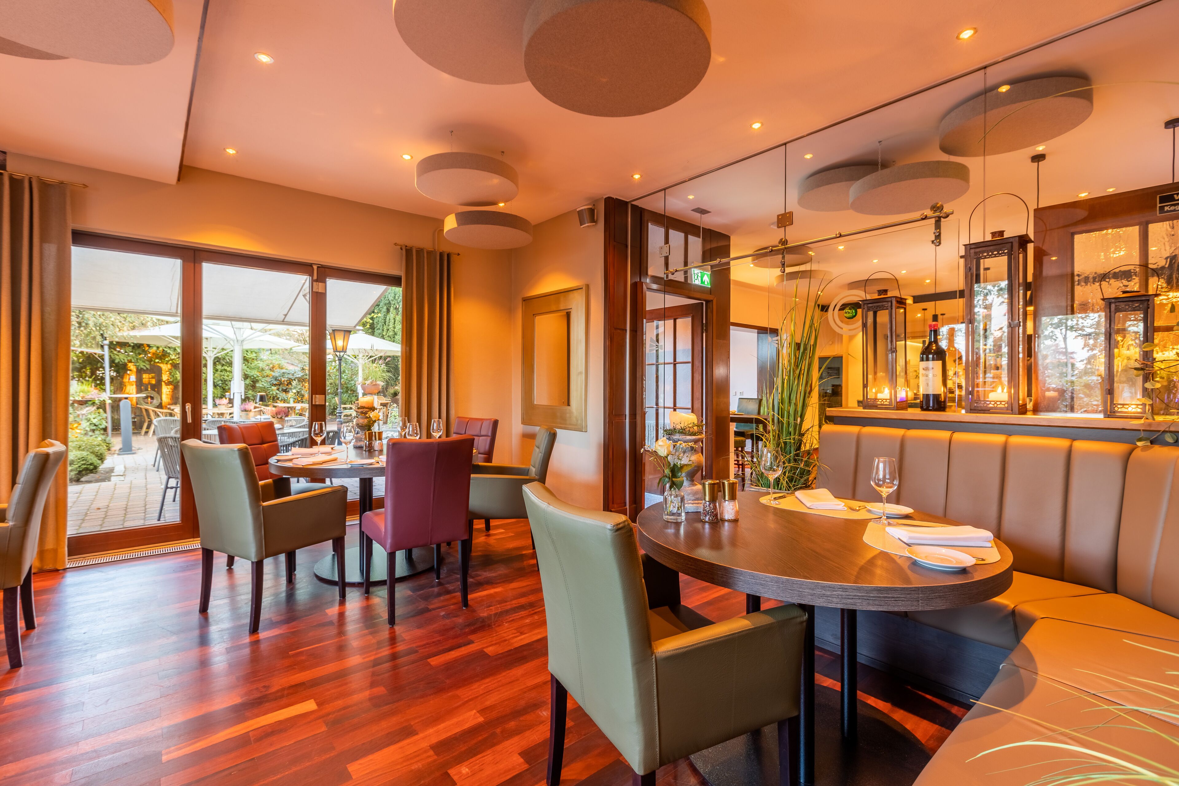 Un restaurante con mesa de madera, sillas acolchadas y una zona de bar con copas.