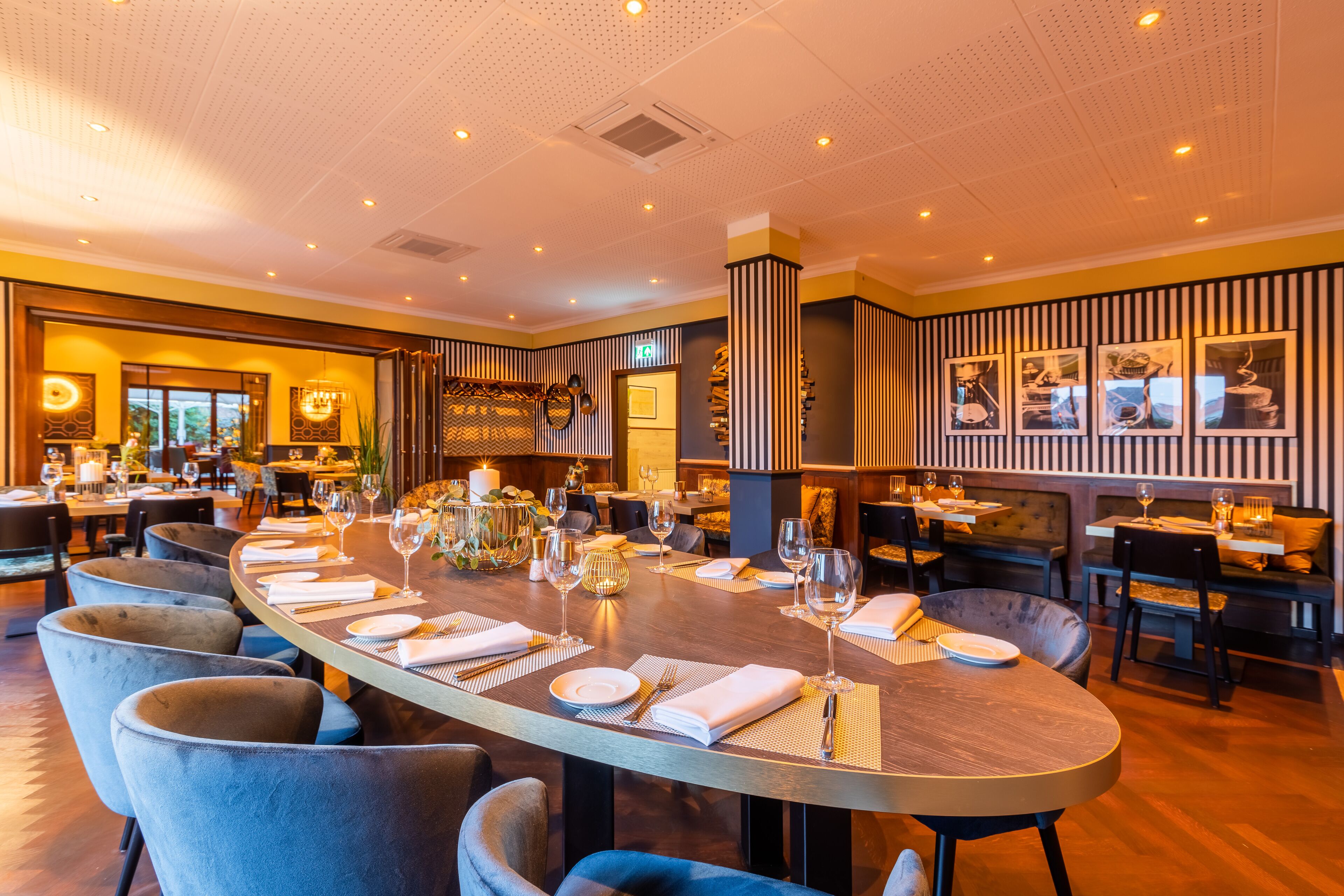A spacious dining area with a long table set for a meal, surrounded by comfortable seating.