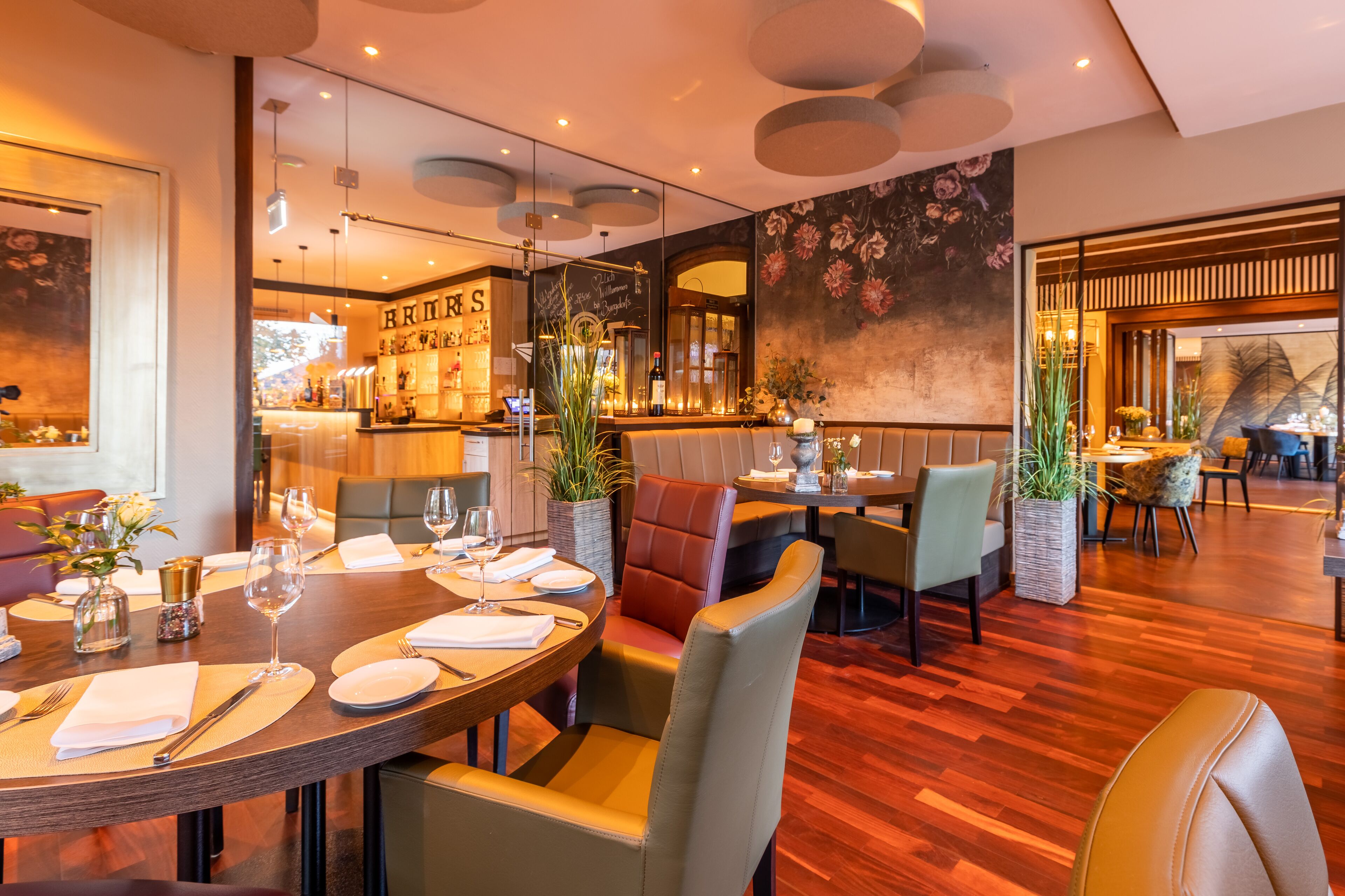 Un restaurant doté d’un bar, d’un sol en bois et d’une décoration moderne.