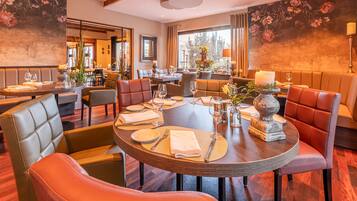 A restaurant with round tables, leather chairs, and floral wall art.