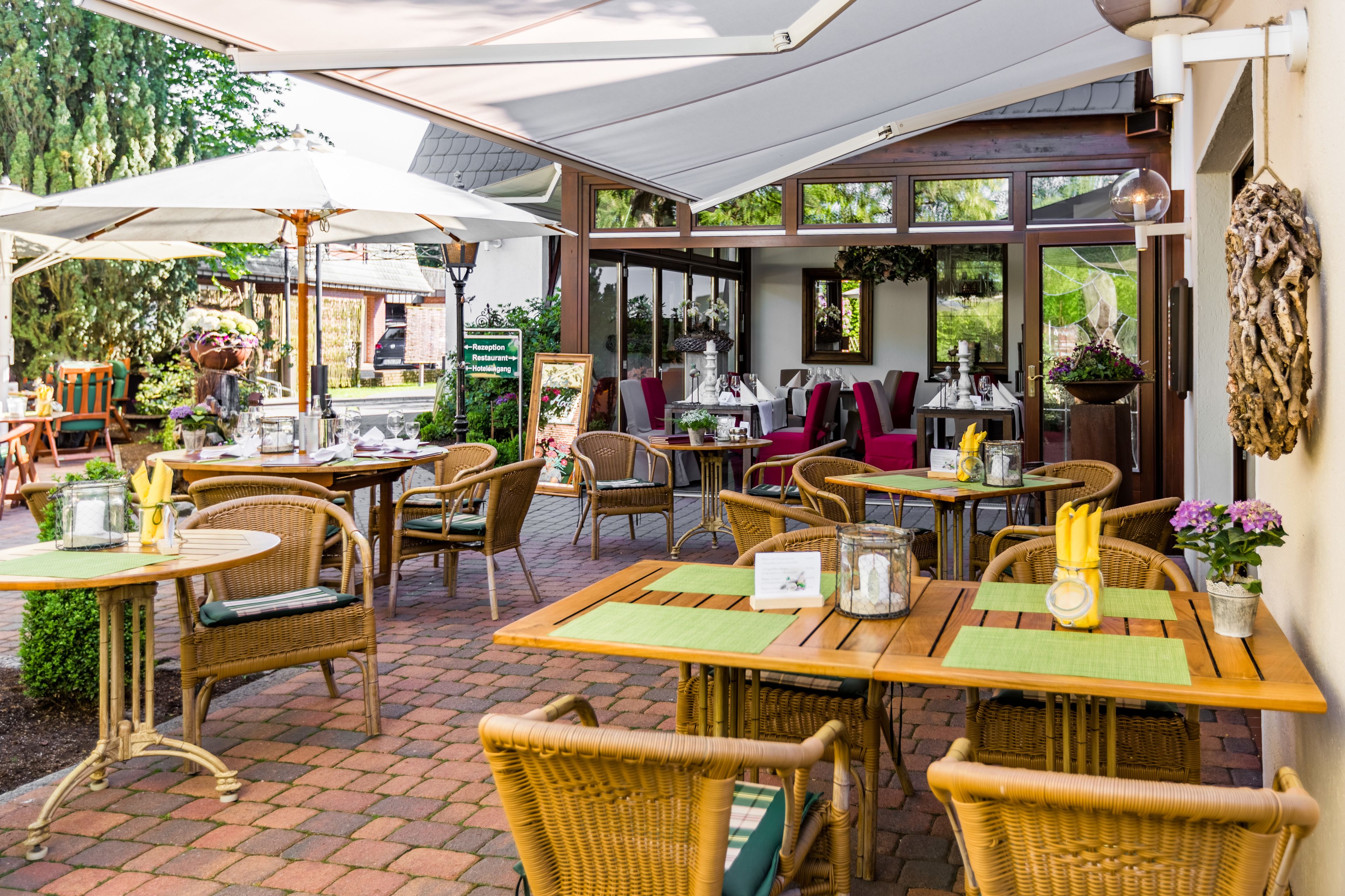An outdoor patio area with wicker furniture, tables, and umbrellas.