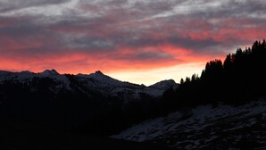 A mountainous landscape with snow-covered peaks and a sunset sky. - Logis HOTEL Restaurant U'FREDY (La Clusaz)