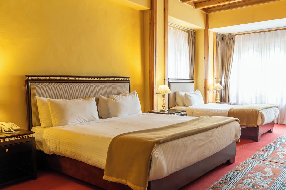 A hotel room with two beds, a telephone on the nightstand, and a patterned carpet.