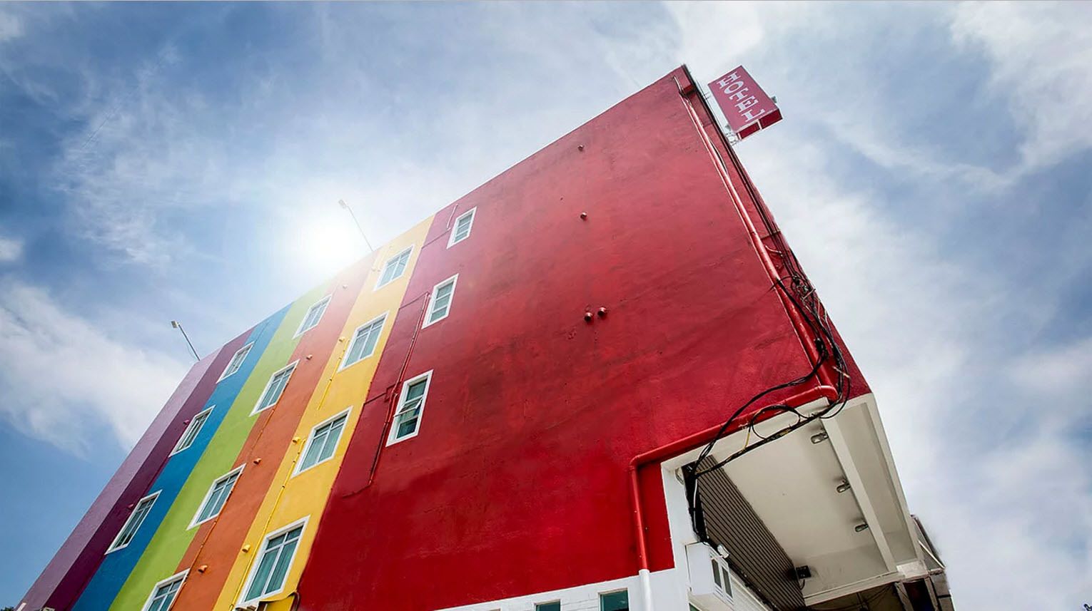 A multi-story building with a red section on the right and colorful sections on the left.