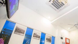 A reception area with a flat-screen TV, a ceiling fan, and a wall-mounted air conditioner. - Skyview Hotel (Chukai)