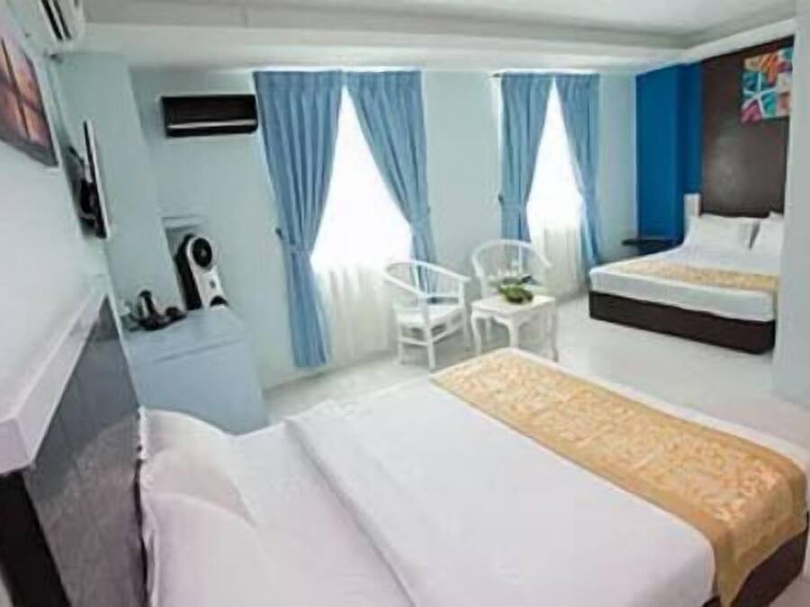 Habitación de hotel con dos camas, un escritorio y una silla.