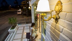 A woman exiting a building with a white door and a large, ornate wall-mounted lamp. - Skyview Hotel (Chukai)