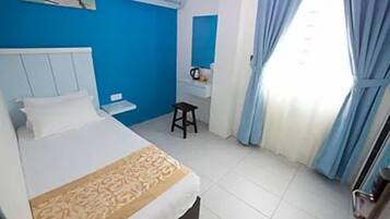 A bedroom with a bed, a small stool, a desk, and a window with curtains.