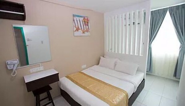 Habitación de hotel con cama, escritorio, teléfono y ventana con cortinas.