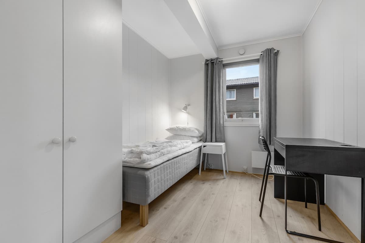 A bedroom with a bed, a desk, and a chair.