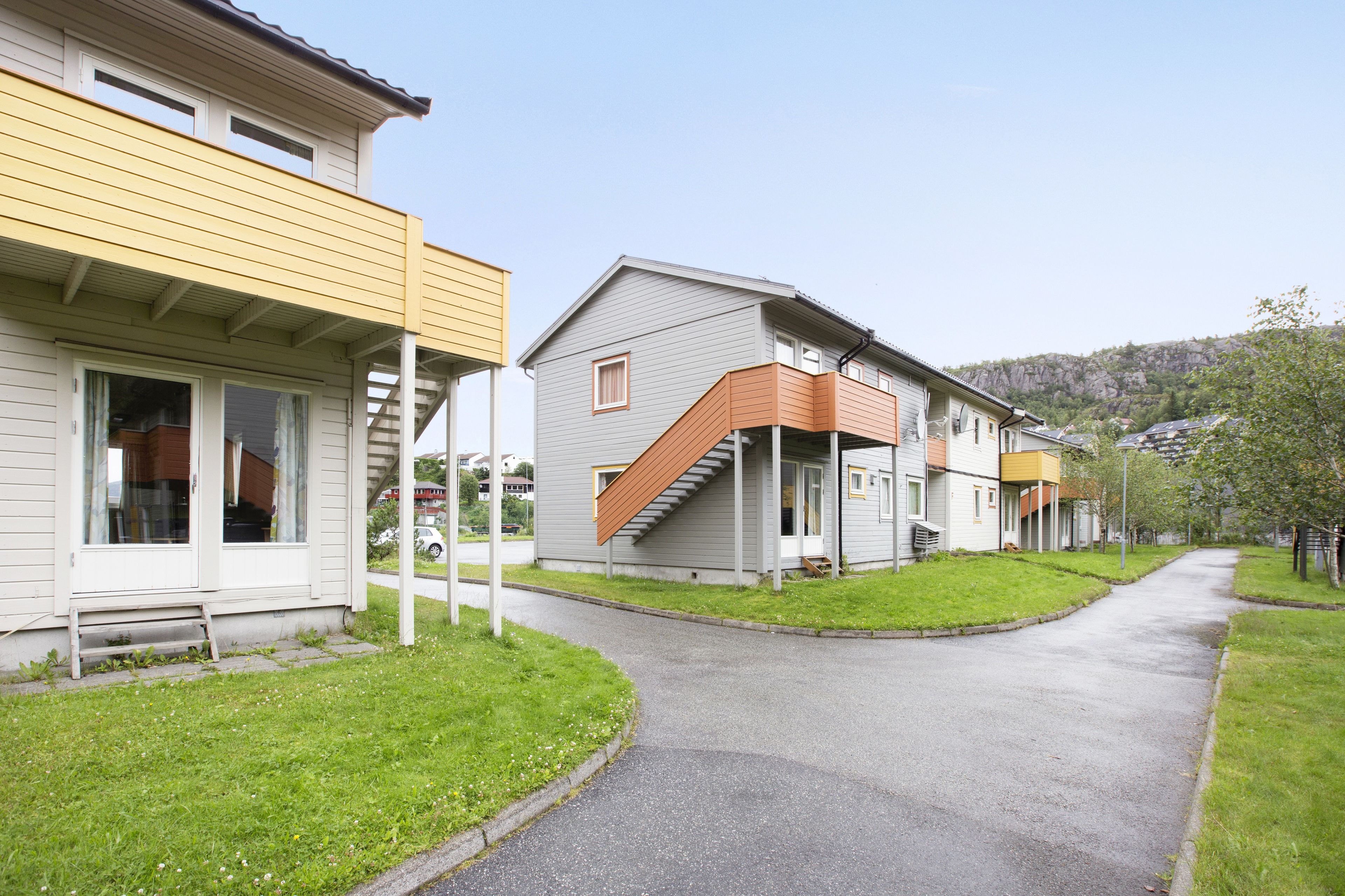 Une rangée de maisons modernes à deux étages, dotées d’un porche couvert et d’un escalier menant à l’étage supérieur.