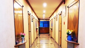 A hotel hallway with doors on both sides, a polished floor, and small tables with flowers. - The Bavana Surawong Bangkok (Bangkok)