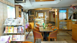 A restaurant with a long counter, multiple chairs, and a display of magazines on the left. - The Bavana Surawong Bangkok (Bangkok)