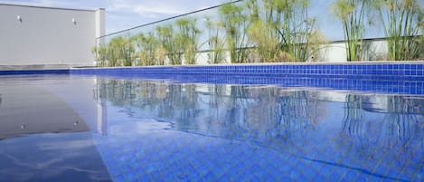 Una piscina al aire libre, sillones reclinables de piscina