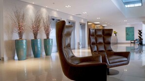 A modern lobby with two leather chairs, a decorative wall, and a large window. - Gran Executive Hotel (Uberlandia)