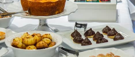 Una mesa de buffet con diversos postres, incluyendo un pastel nordés, eclair y otras pastas.