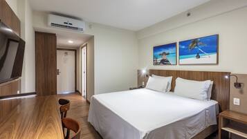 Una habitación de hotel con una cama grande, un escritorio de madera y dos cuadros en la pared.