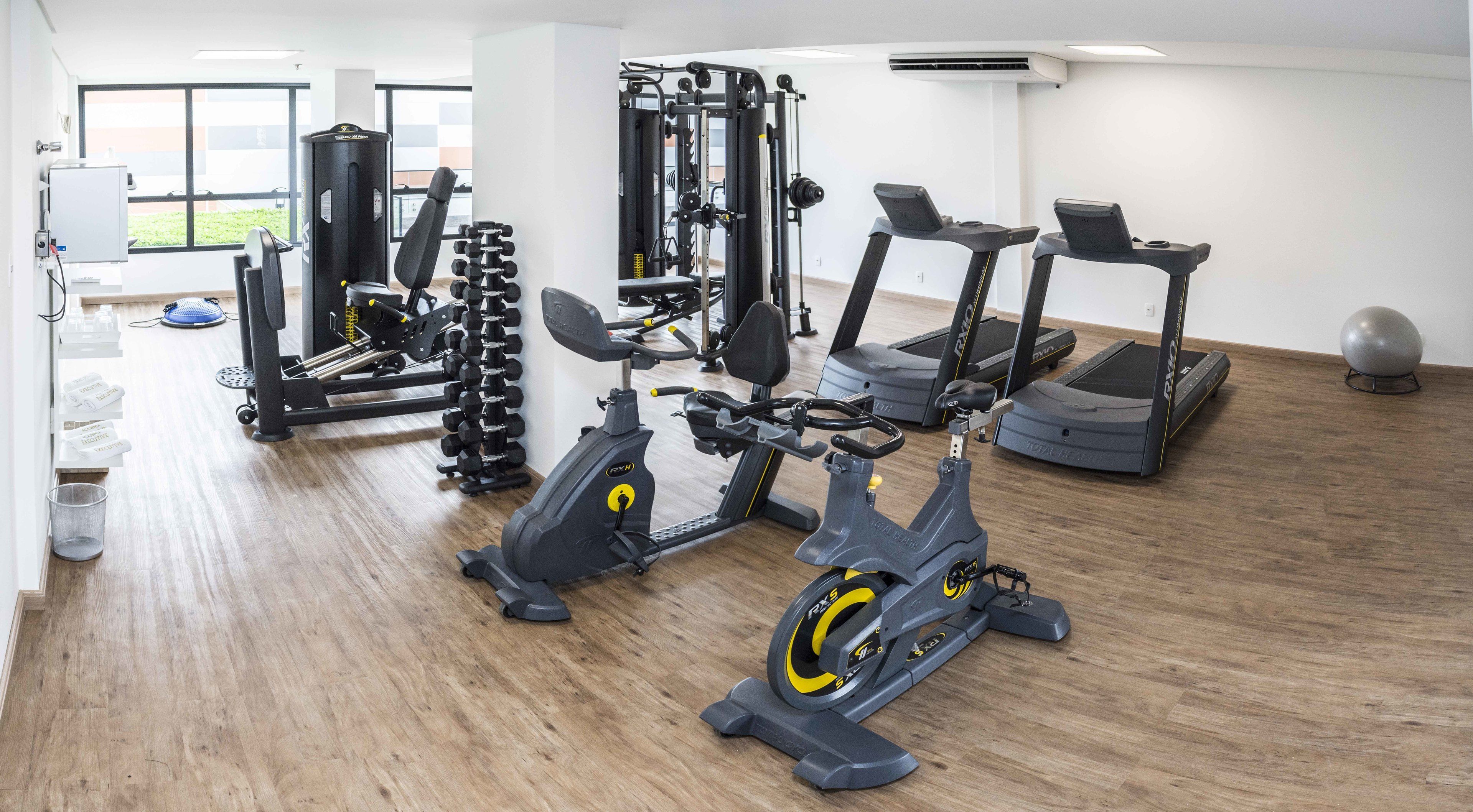 A gym with cardio machines, weight training equipment, and a large window.